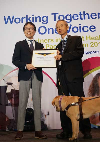 シンガポールの受賞式にて表彰を受ける武田飛呂城事務局長